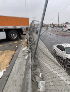 Technician reporting a chain-link fence in a commercial area.